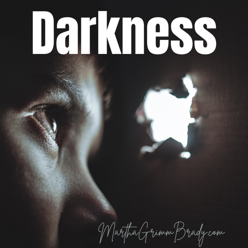 woman in dark looking out hole to see glimmer of light.