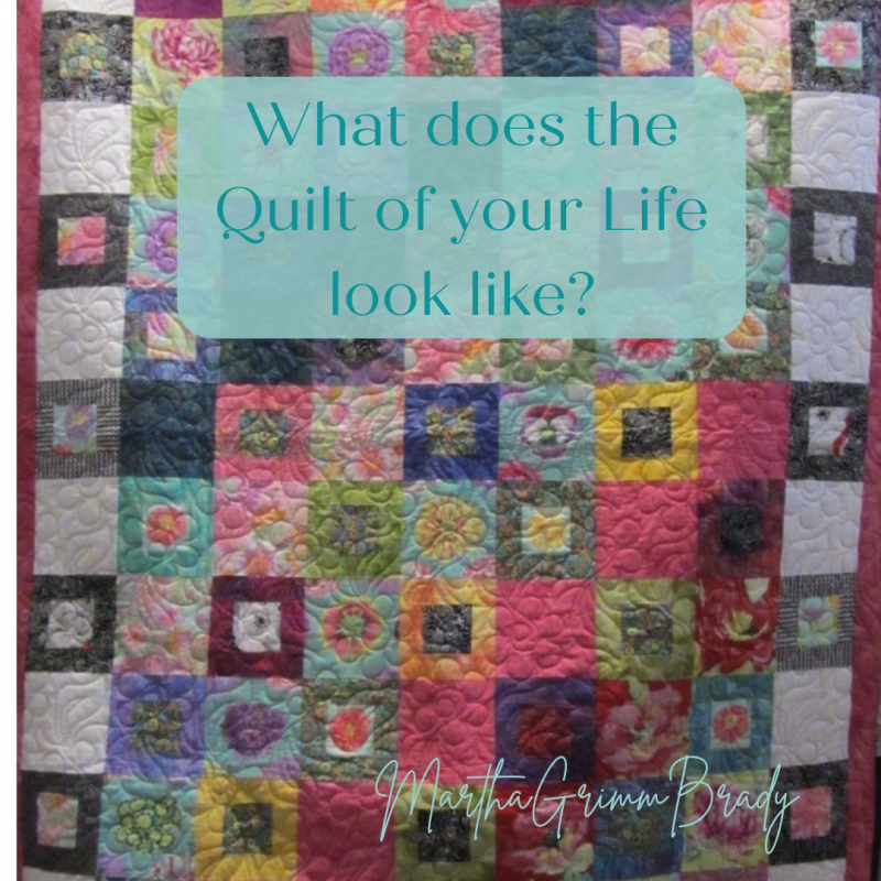Photo of quilt made of squares in varying shades of pinks, yellows, purples and blues.