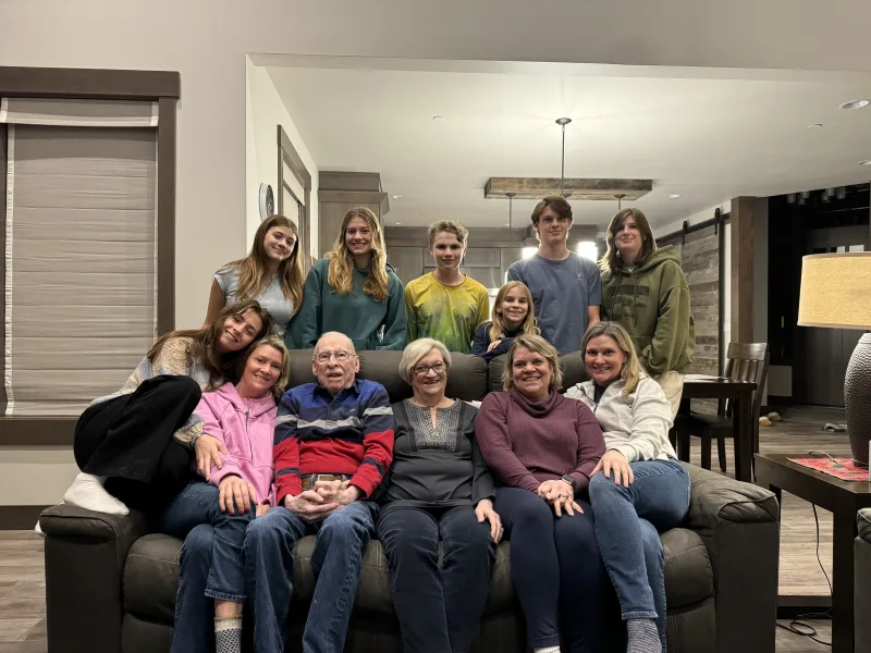 Photo of large family group in vacation home includes grandparents, parents and children. The two fathers aren't in the photo.